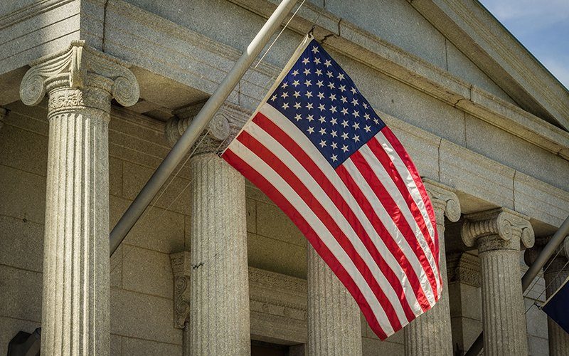 Image shows a courthouse with an American flag outside