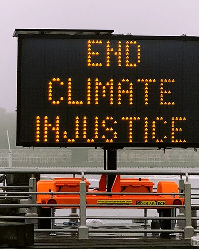 Image shows a sign saying "end climate injustice"