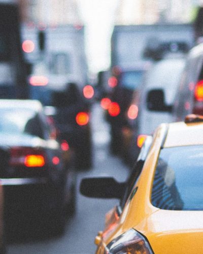 A photo of New York City traffic, viewed from the bumper of many taxis and cars waiting at an intersection
