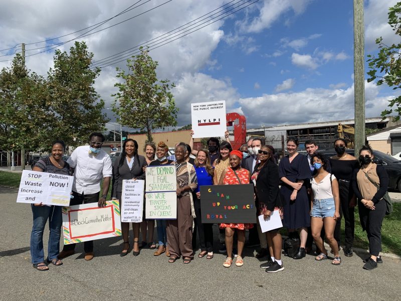 Jamaica Residents and environmental advocates pose after the press conference with environmental protest signs.